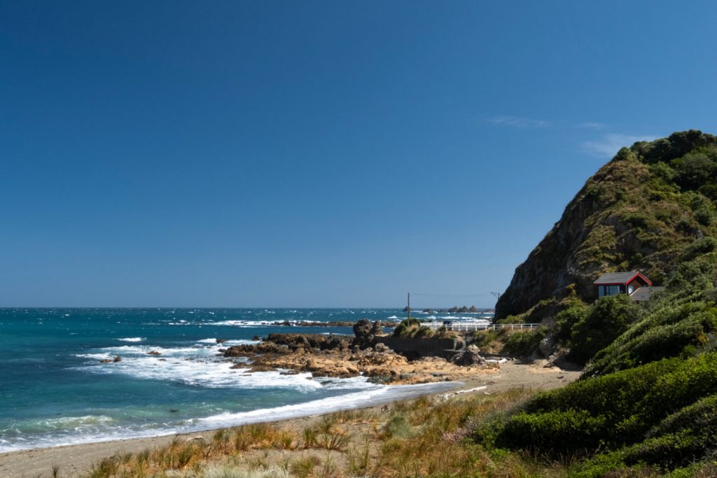 Waves crashing on the shore of a bay in Wellington, New Zealand on a beautiful sunny day on the Southern Walkway track.