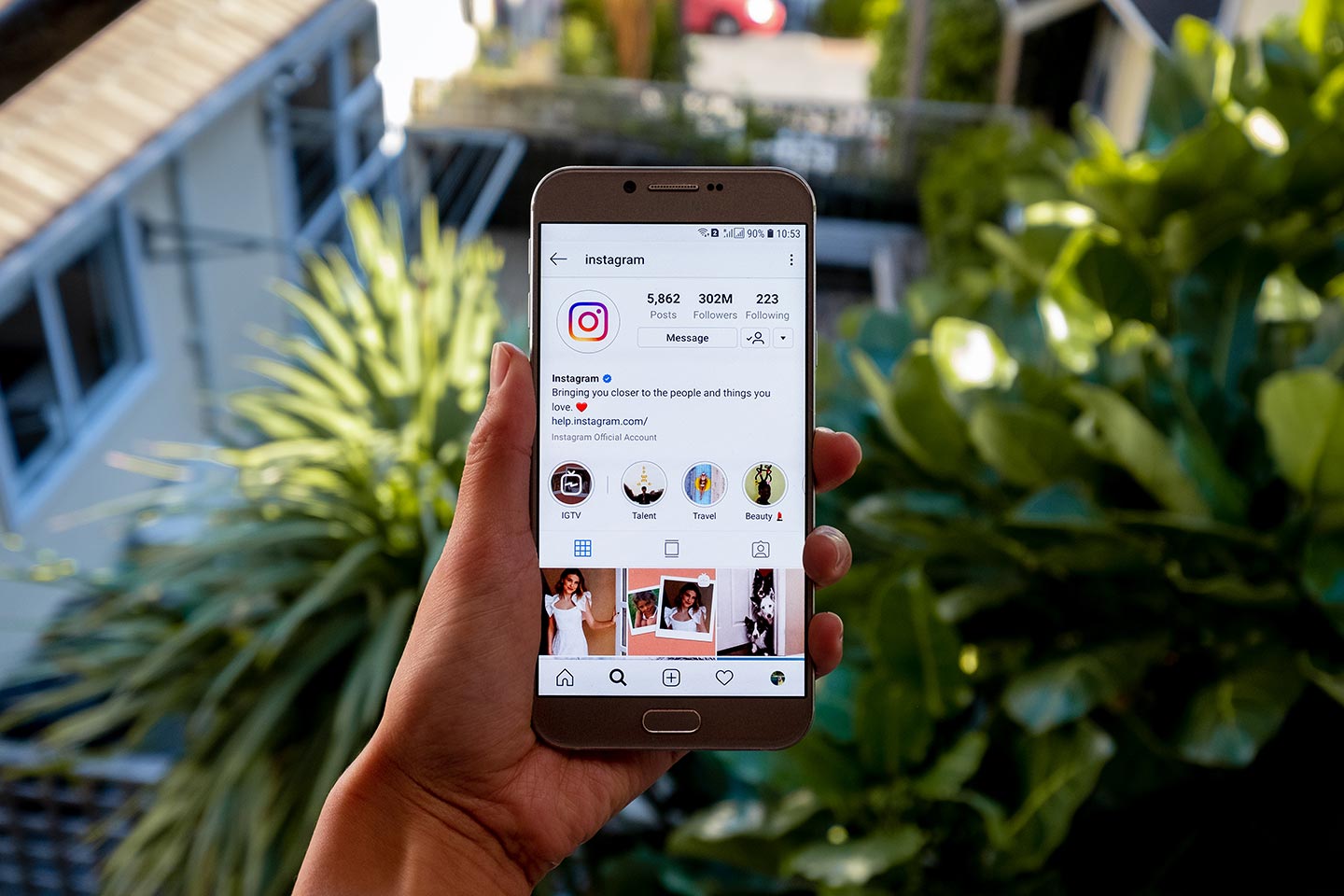 A womans hand holding a smartphone. On the phone you can see she has the Instagram app open and is looking at Instagrams profile.