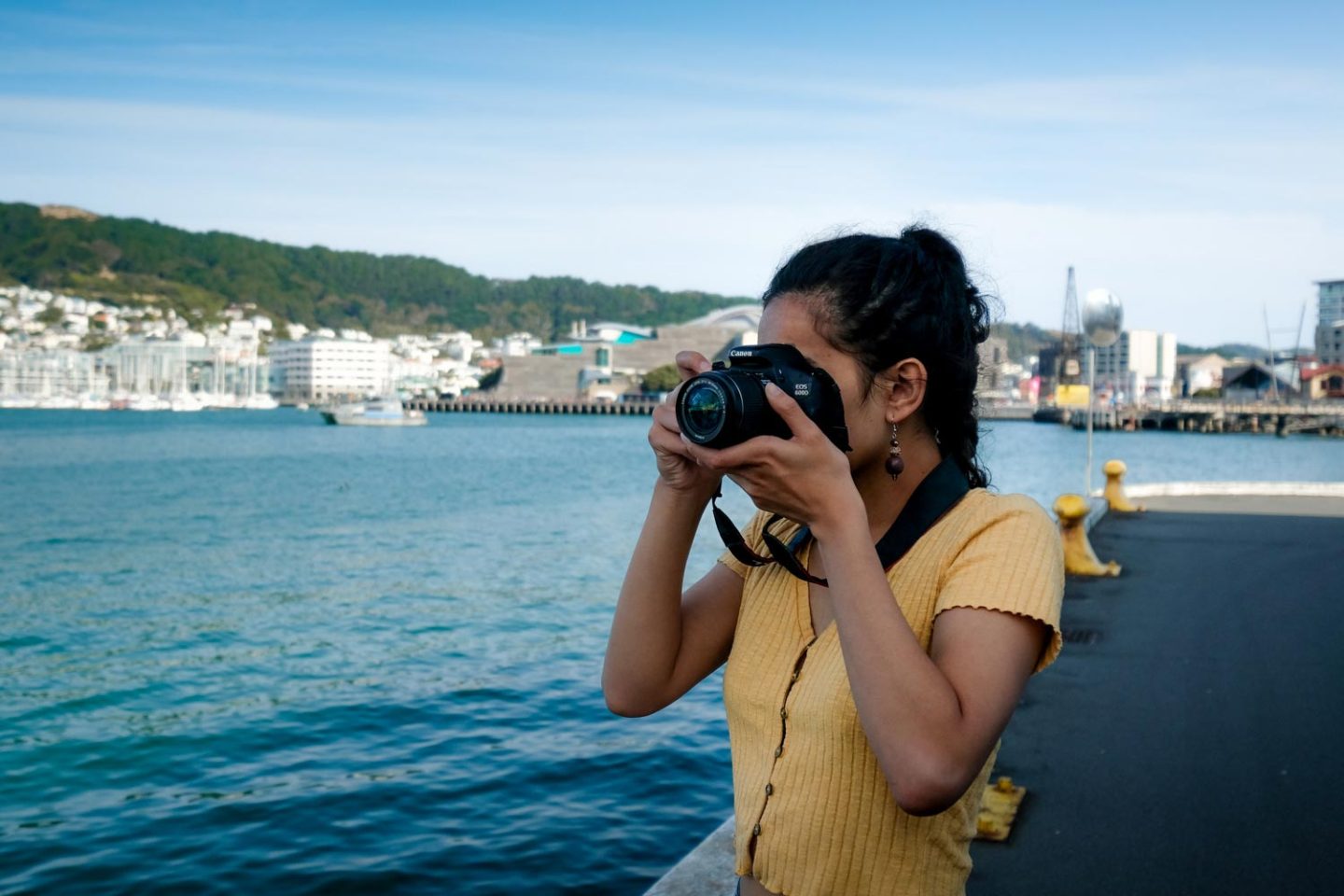 A young women taking a photo with a camera while she travels around the world. Someone who could benefit from this list of must-have photography accessories.
