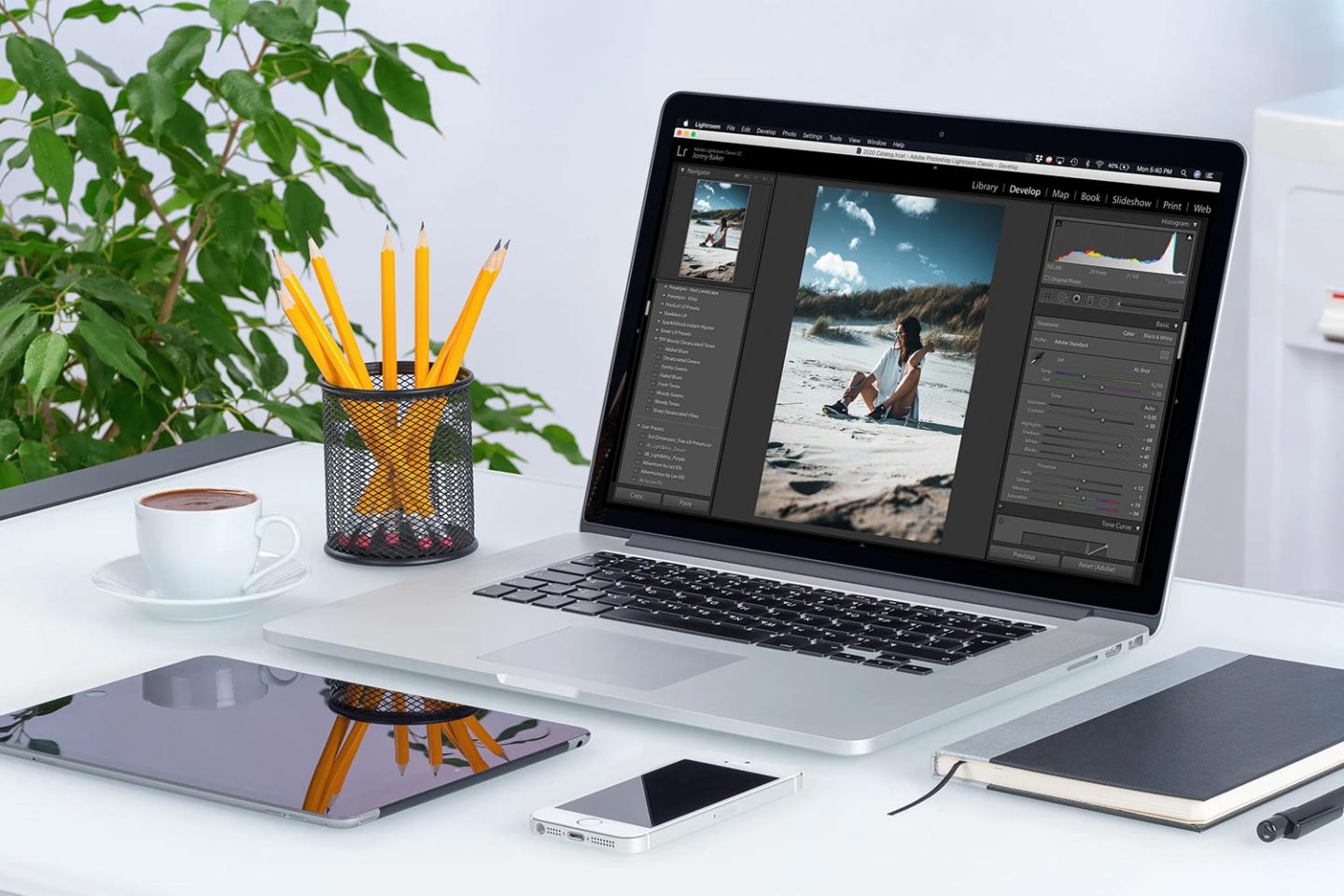 A laptop on a desk with Lightroom open a photo of a woman on a beach is being edited.